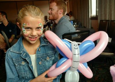 Girl with face paint holding butterfly balloon creation